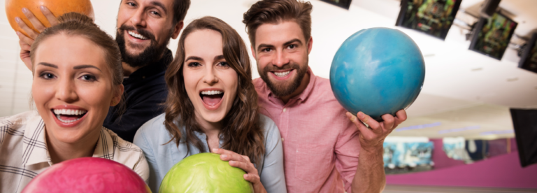 Two men and two women with colorful bowling balls ready for a great bowling party.