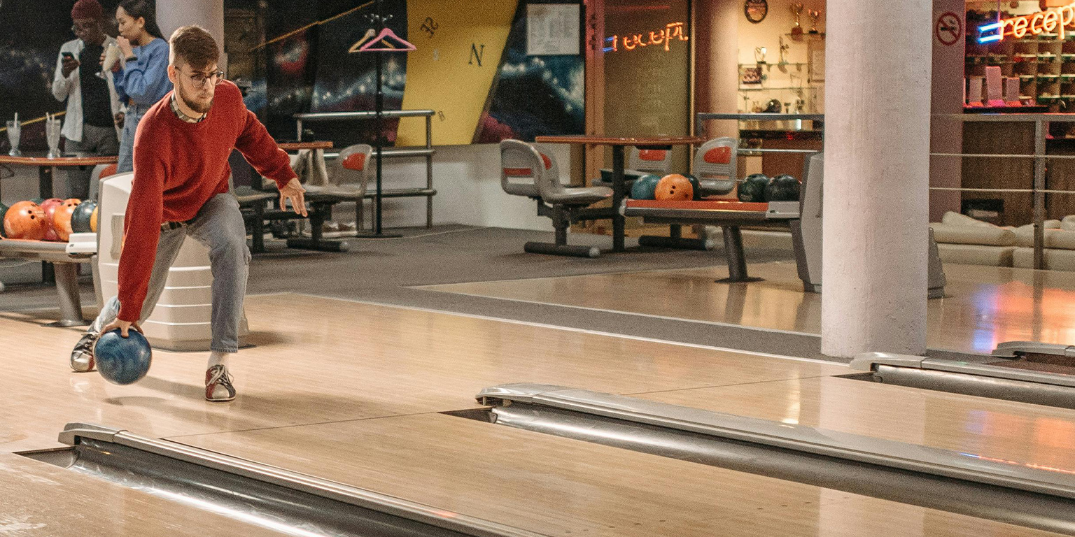 A bowler throwing a bowling ball down the bowling lane
